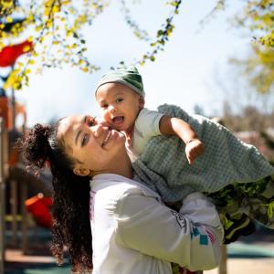 Smiling woman holding smiling baby near play structure