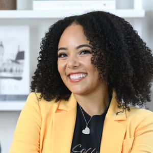 Photo of Breea Wainright, an African-American woman with short curly hair, wearing a yellow blazer and smiling. 