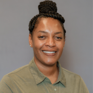 Photo of Shayla. She is smiling to the camera, wearing a green collared shirt, and wearing a bun. 